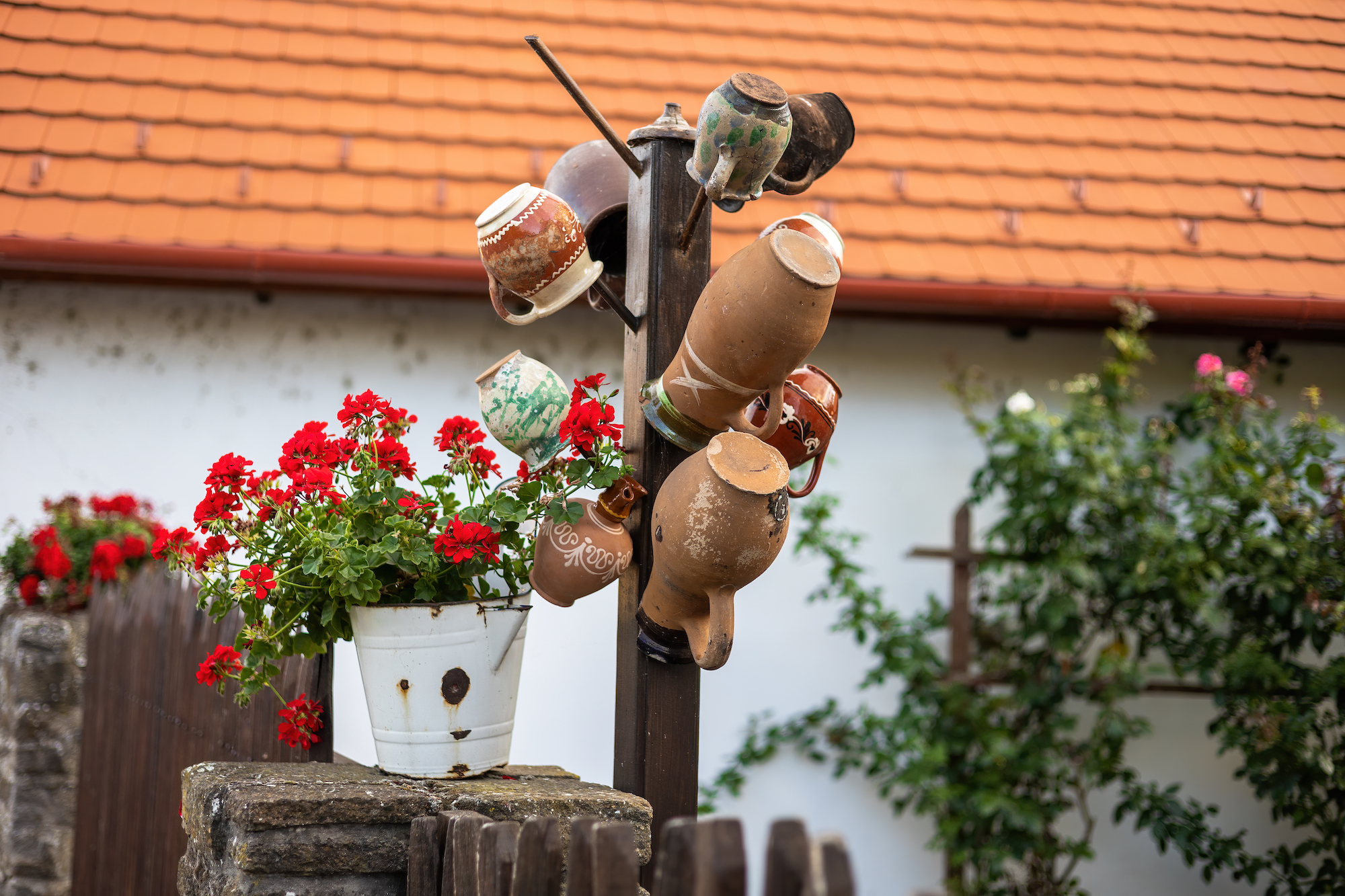 Several ceramic cups stored hanging on a fence in village in Hungary. Concept of a traditional art and hand made craft in a historical part of a city. Pottery made of mud on a display.